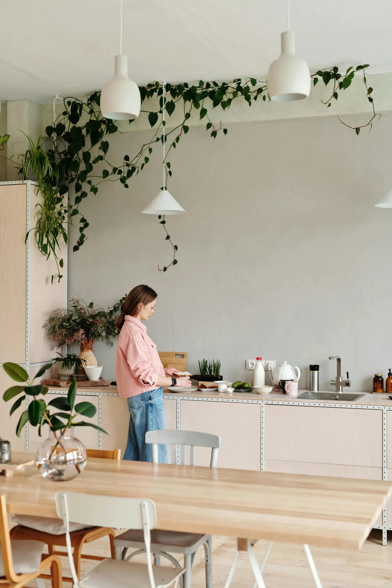Lyst kjøkken med spisebord, hengeplanter og pendellamper